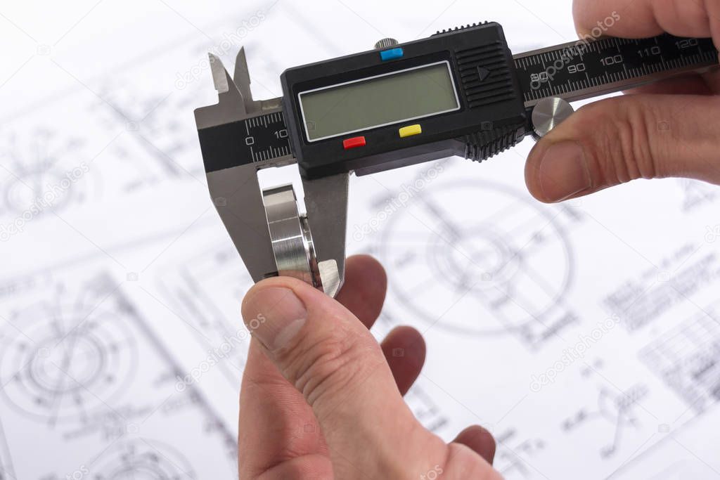Measuring a steel part with a vernier caliper in a person's hand. Quality control. Engineer when measuring the diameter of a metal roller with a precision tool. Project plan.