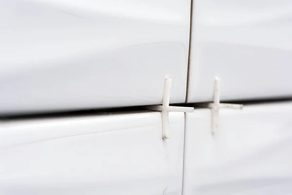 Σταυροί σε λευκό πλακάκι. Κοντινό πλάνο. λευκό πλακίδιο κολλημένο στον τοίχο με λευκό πλαστικό (πολυπροπυλένιο) σταυρούς. — Φωτογραφία Αρχείου