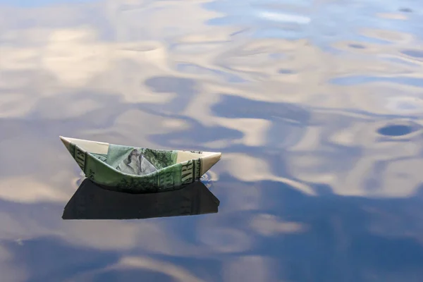 Origami boat built of one hundred dollar bill. paper boat from a hundred dollar bill in blue water. copy space. Concept: investment, finance. — Stock Photo, Image