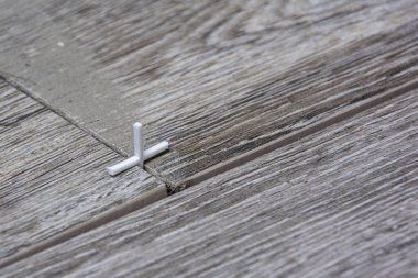 Zemini seramik fayanslarla döşemek. Dikişleri hizalamak için plastik haçlar kullanın. Yakın plan..