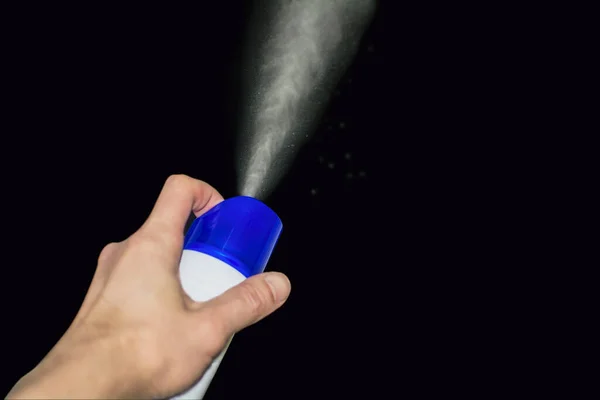 man\'s hand holds a spray can and sprays an air freshener.