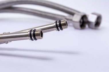 Hidrolik metal hortum beyaz arka planda bitiyor. Yakın çekim. Fındıklı su hortumları. Tesisat malzemeleri. Tesisat tamiri.