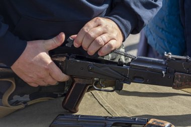 Yaklaşan erkek eller makineli tüfek tutuyor, seçici odaklanma. Elde. Adamın biri makineli tüfek tutuyor. Savaş konsepti, egzersizler. Silahlar erkeklerin elinde..