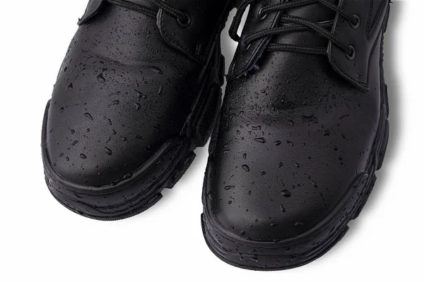 Vízcseppek fekete bőrcipőkre. Fehér háttérrel definiálva. Koncepció: cipők feldolgozása és gondozása, víztaszító hatás, rossz időjárás. — Stock Fotó