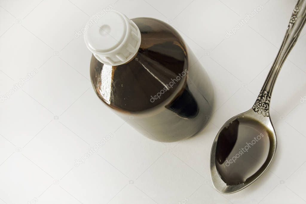 bottle and cough syrup in a spoon. Close Up of a natural cough medicine in a spoon. View from above. Concept: treatment and health.