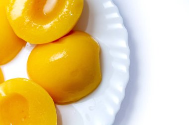 Beyaz tabakta konserve şeftali. Arka planda beyaz bir tabakta meyveler. yakın plan