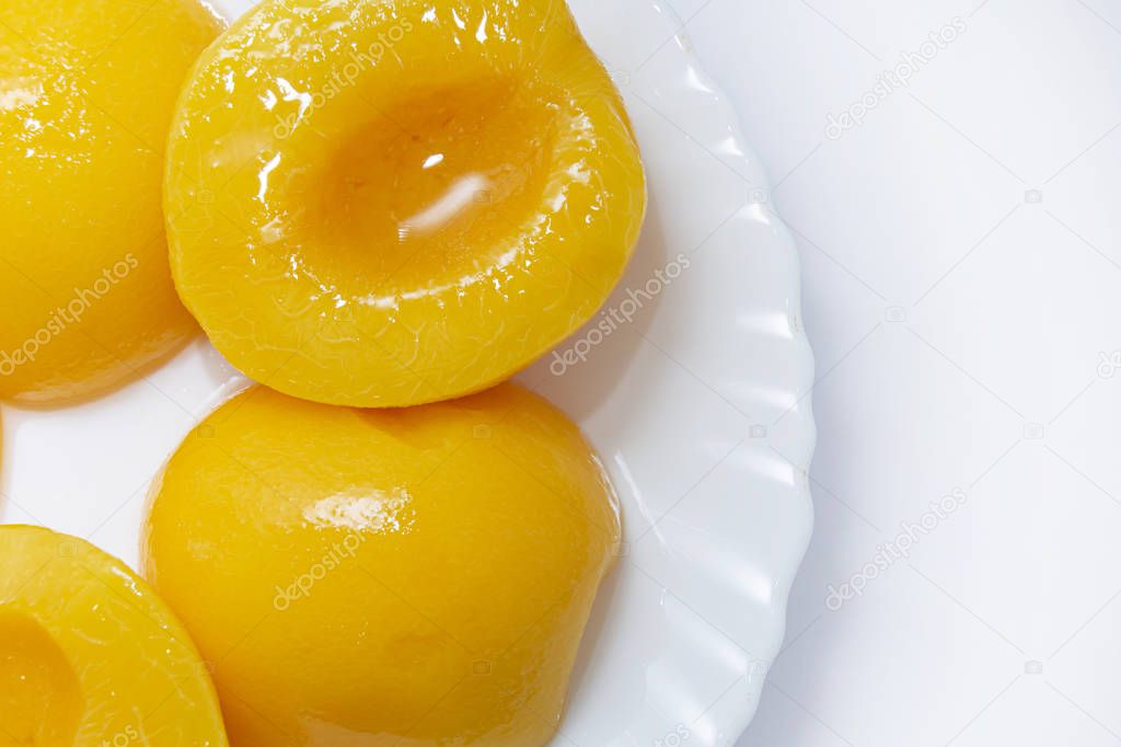 canned peaches on a white plate. Fruits on a white plate on a light background. close-up