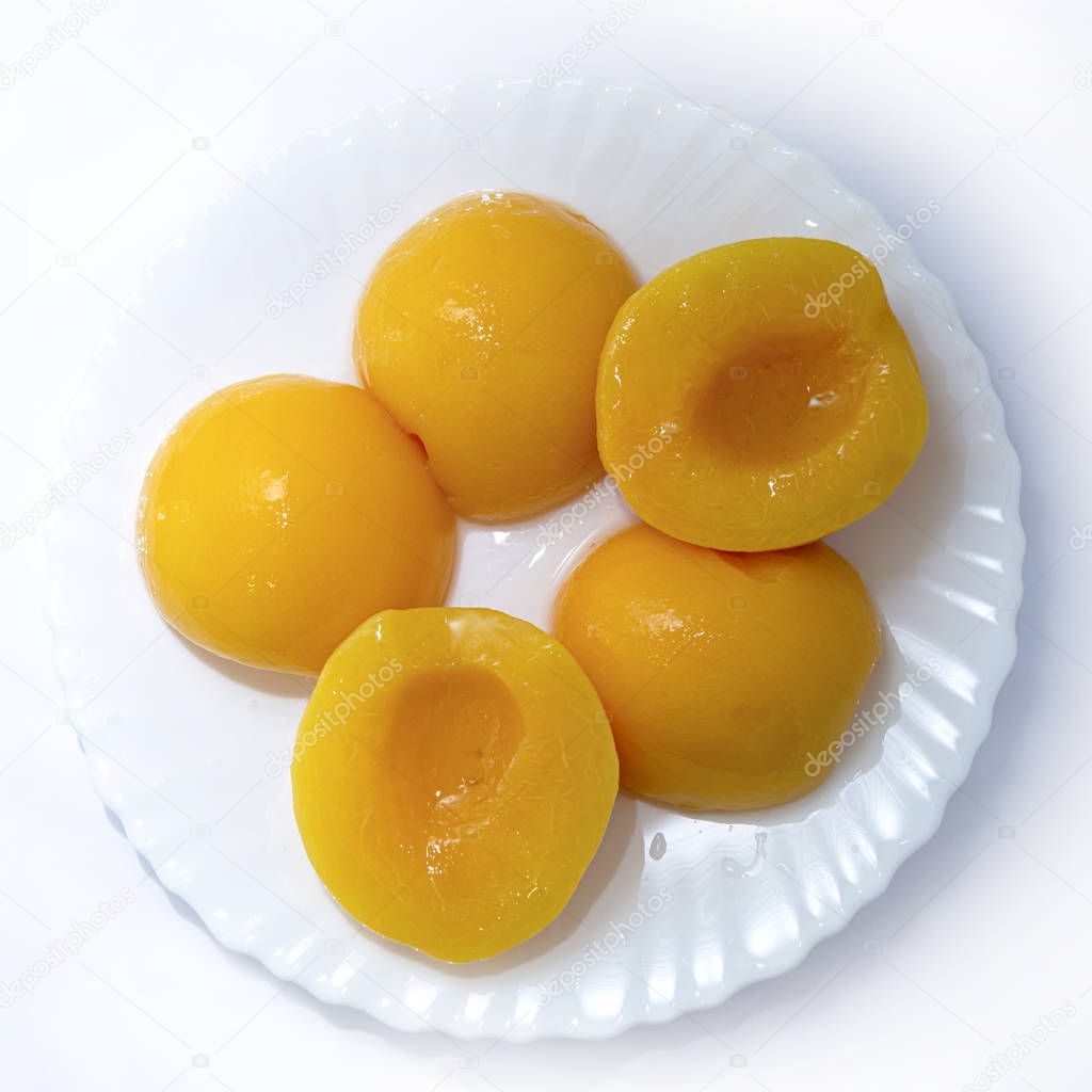 plate of peeled and chopped peaches isolated on a white background. Canned peaches on a white plate. View from above.