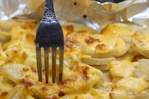 Rosti burgonya sajttal, közelről. Egy villa átszúrja a krumplit sajttal. Növényi növekedés, burgonyapalacsinta sült burgonyával és sajttal. — Stock Fotó