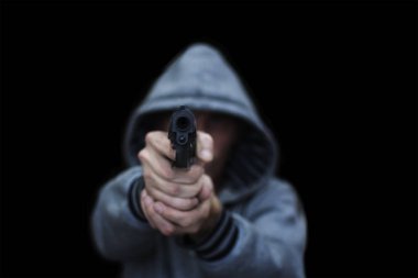 Bir adam tabancayla nişan alır. Siyah bir arka planda izole edilmiş. Tehdit kavramı, tehlike, savunma