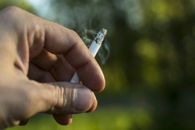 Sigarayı tutan bir elin yakın çekimi.