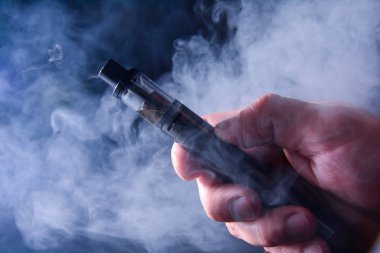 Dumanın arka planında elektronik bir sigaranın soyut görüntüsü. Uzayı kopyala Sigara içmenin tehlikeleri, sigaraya alternatif, kötü alışkanlıklar..