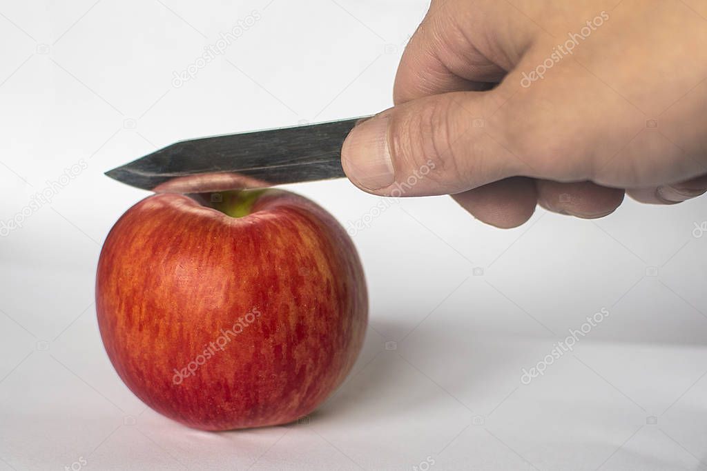 Man cuts a red apple with a knife. hands cutting red apple