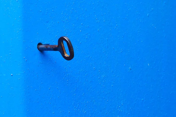 Vieille clé dans le trou de serrure. Porte en métal bleu avec une surface texturée. Concept : interdiction et inaccessibilité, secret, confidentialité . — Photo
