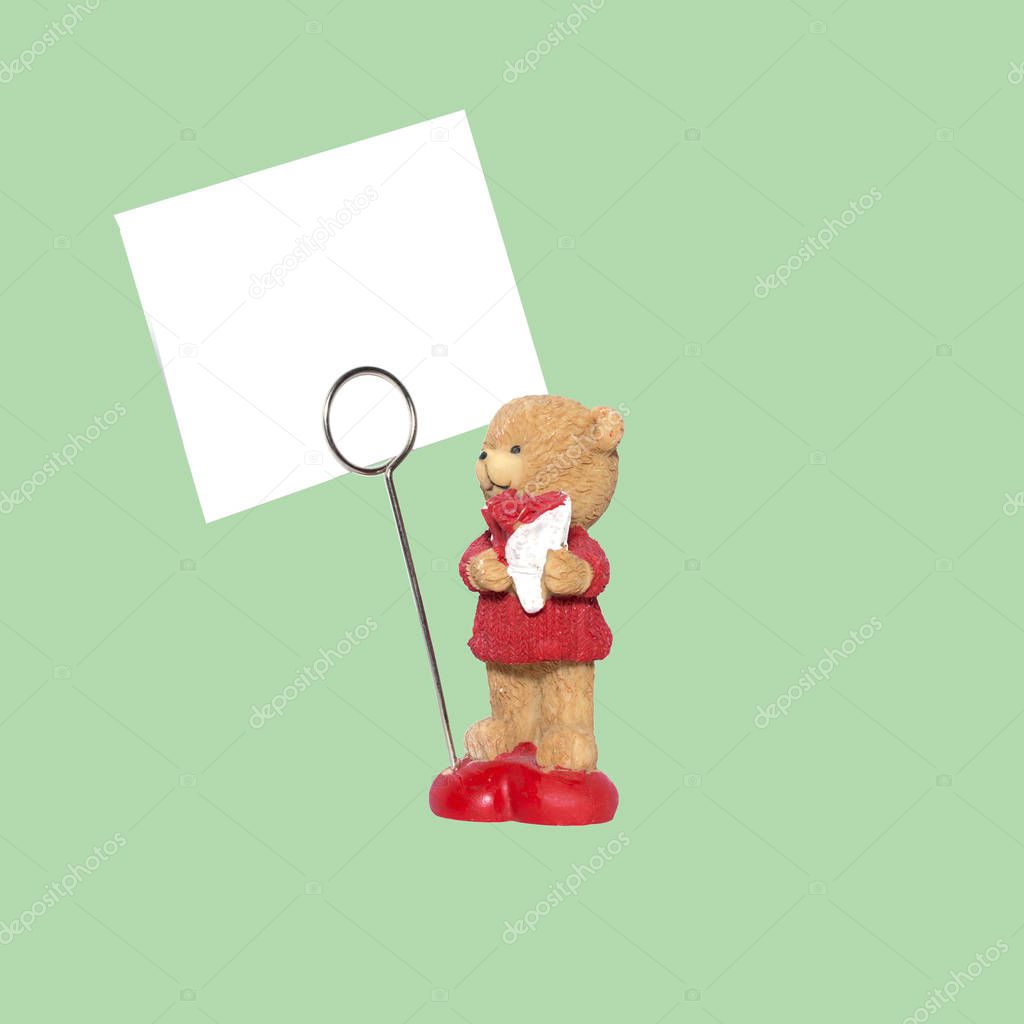 clay decorative figurine of a bear with a bouquet of flowers and a sign for the inscription. mockup. Isolated on green background object for the project and design.