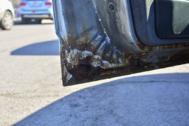 Paslı bir arabanın parçası. Paslı bir araba kapısının parçası. Arabanın gövdesi aşınmış. Konsept: Aşınmaya dayanıklı, araba tamircisi, pas. Koruma.