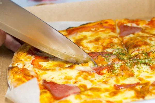 Close-up. Cuts freshly delivered pizza. Concept: delicious food, pizza day.