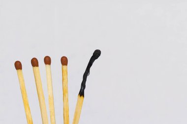 A burnt matchstick among those not burnt down. Concept: international matchstick day, teamwork, dedication, different from others, alone.