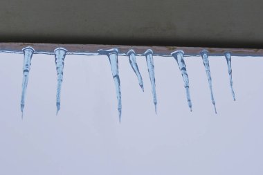 Icicles on the eaves. Concept: thaw and spring, the danger of ice and icicles on the roof, night frosts.
