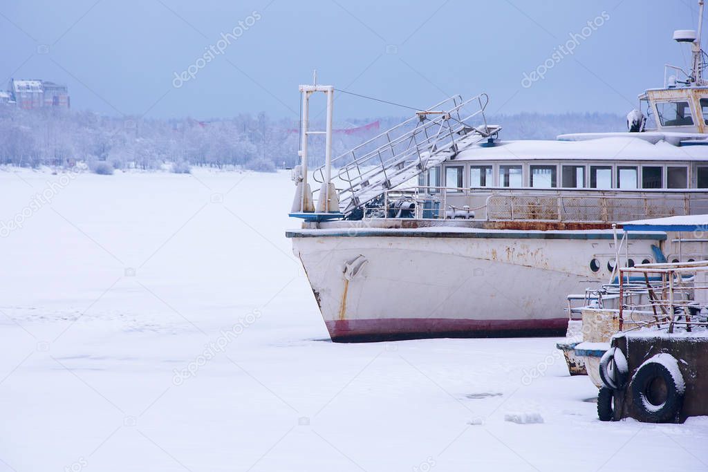 Old rusty ship in the winter at the pier. frozen river. soft focus.