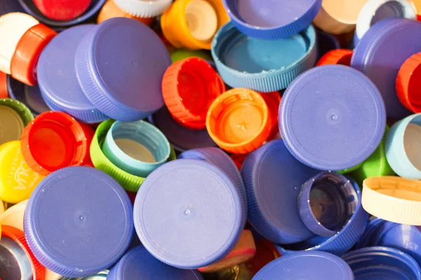 Muchas tapas de botellas de plástico multicolor, primer plano. Concepto: eliminación de residuos, protección medioambiental . — Foto de Stock