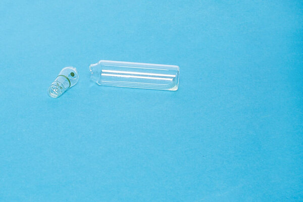 open empty ampoule on a blue background. Concept: health, medical care, vaccination.