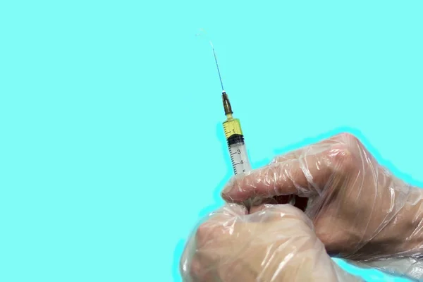 Gloved hands holding a syringe. Object isolated on blue background. Concept: vaccination, first aid, vaccinations during an epidemic. — Stock Photo, Image