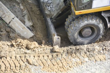 İnşaat ekipmanlarına yakın çekim. Kazıcıyla toprak çıkarma. Geliştirme ve inşaat, yol çalışmaları. Parkın peyzajı üzerinde çalışıyor..