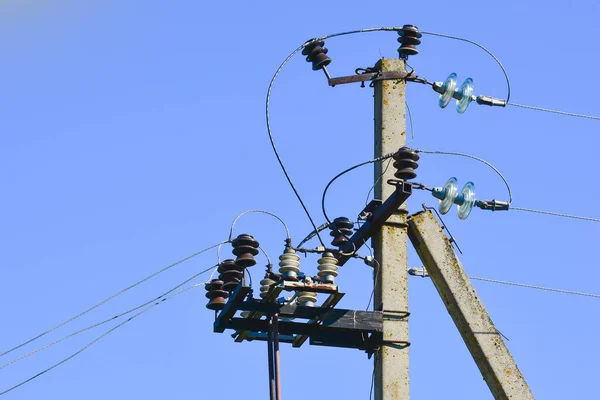 Pilastro della linea di trasmissione elettrica con isolanti trasparenti. Fotografato da vicino. Contro il cielo blu — Foto Stock