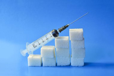 Şırınga ile şeker küpleri. Diyabet kavramı. Şekerden gelebilecek olası zarar kavramı. Kan şekeri düzeylerinde artış, şeker küpleri ve şırınga üst büyüme grafiği.