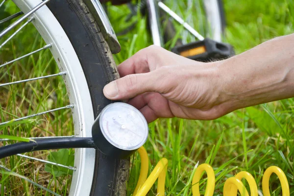 Egy személy felfújja a kerékpárt sűrített levegővel és nyomásmérővel. Kerék és kéz lágy fókuszban a háttérben. — Stock Fotó
