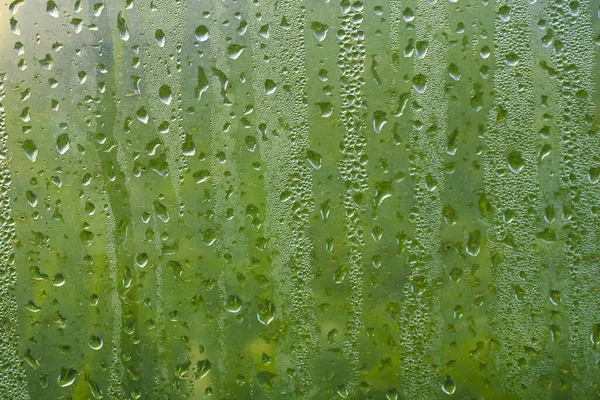 Влажная прозрачная пластиковая пленка с капельками воды после дождя. Вода капает близко. Дождевой фон. Дождевая погода — стоковое фото