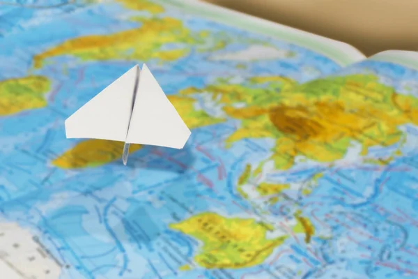 Mały papierowy samolot nad geograficzną mapą świata. selektywne skupienie. Koncepcja: podróże lotnicze, dostawa ładunków, podróże, wiadomości międzynarodowe, poczta. — Zdjęcie stockowe