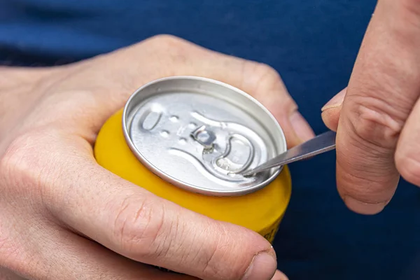 Man\'s hands open a can of beer with a knife. Defective jar did n
