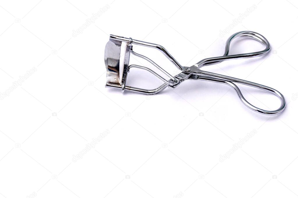 Tool for curling eyelashes on a white background. Close-up. Copy space.