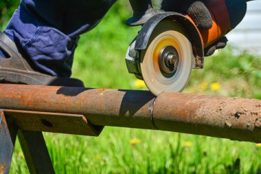 Açı öğütücüyle çeliği kesen ağır endüstri işçisi. Paslı bir boruyu kesiyorum. Sökülüyor.