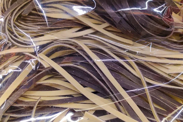 Bunte Nudeln sind in Zellophan-Verpackungen verpackt. Abstrakter Pasta-Hintergrund. — Stockfoto