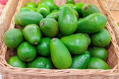 Hasır sepette bir sürü avokado var. Marketteki tezgahın üstünde meyve var. Meyve perakende satış kavramı.