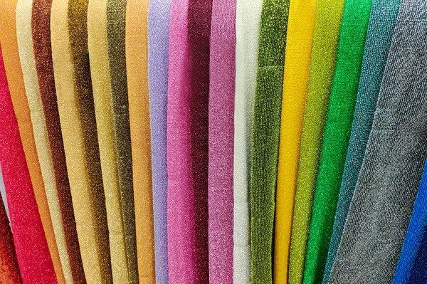 Various multi-colored fabrics. Fabrics in a store on the counter. Colorful abstract background.