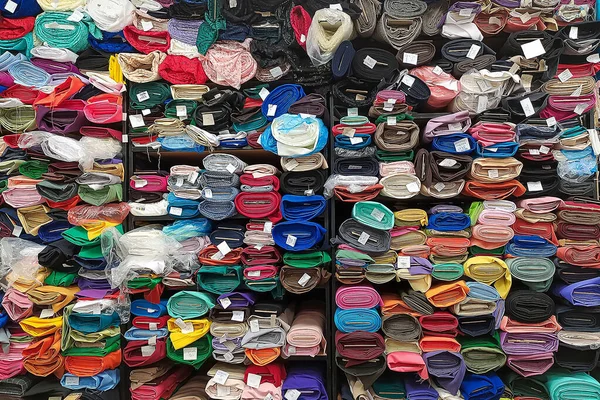 Multicolored fabrics for sale in a store. Rolls of fabric laid out on shelves. Abstract colorful background.