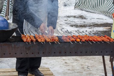 Bir adam barbekü pişirirken et kızartır. Doğada et pişirmek.