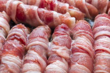 Pastırmaya sarılmış sosisler. Domuz pastırması yakın çekim. Soyut pastırma arka planı.