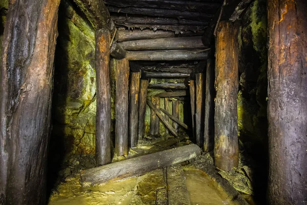 Underground abandoned ore mine shaft tunnel gallery passage with wooden timbering — Stock Photo, Image