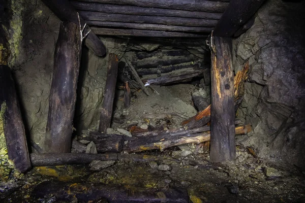 Underground abandoned ore mine shaft tunnel gallery passage with wooden timbering