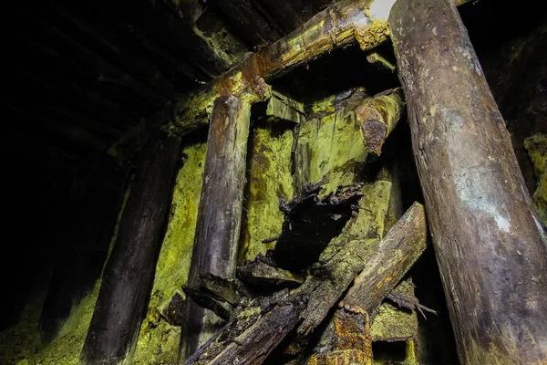 Underground abandoned ore mine shaft tunnel gallery passage with wooden timbering