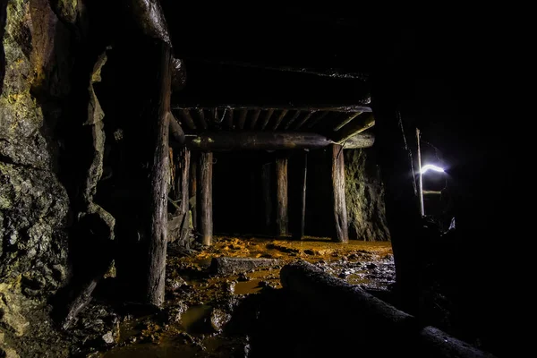 Underground abandoned ore mine shaft tunnel gallery passage with wooden timbering