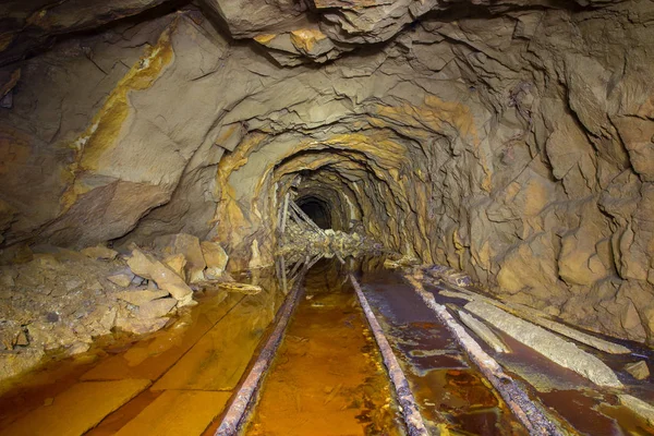 Gold ore mine shaft tunnel gallery with yellow sulfur water underground abandoned