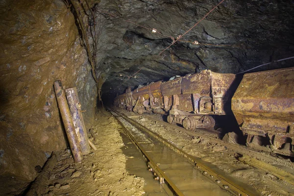 Underground abandoned gold ore mine shaft tunnel gallery passage with ore carts