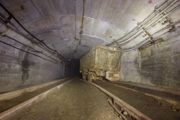 Underground gold mine shaft tunnel drift with rails and wagons mining carts