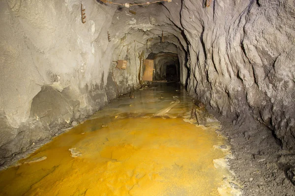 Underground gold mine shaft tunnel drift with yellow water